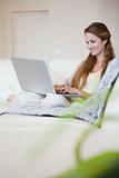 Side view of smiling woman working on her laptop on the sofa