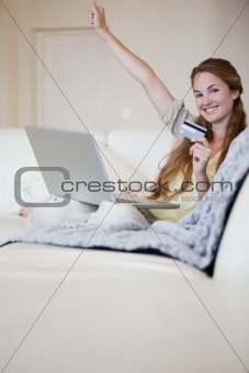 Woman on the sofa celebrating that she won an online auction