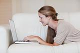 Side view of woman lying on the sofa with her laptop