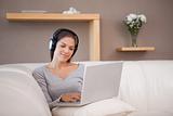 Woman with laptop and headphones on the sofa