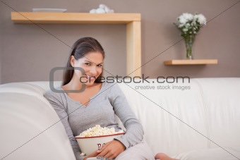 Woman on the sofa watching a movie with a bowl of popcorn