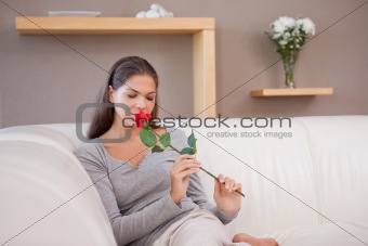 Woman on the sofa smelling on a red rose