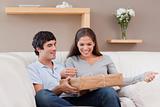 Couple opening parcel on the sofa