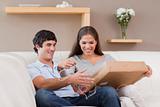 Couple opening parcel on the couch