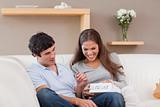 Woman opening present from her boyfriend on the sofa