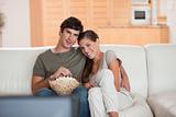 Couple with bowl of popcorn watching a movie on the sofa