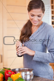 Woman adding spices to her vegetable stew