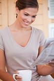 Smiling woman reading newspaper while having coffee