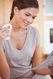 Woman reading newspaper while holding cup of tea