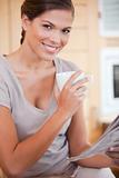 Woman drinking tea while reading newspaper