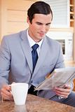 Businessman in the kitchen reading news and having coffee