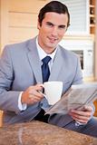 Businessman having coffee and reading news in the kitchen