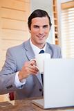 Smiling businessman with laptop and coffee