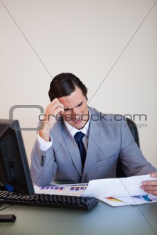 Businessman getting a headache from looking at paperwork