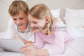 Smiling siblings using a tablet computer