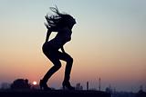 silhouette of slim seductive woman standing on  rooftop at sunset. urban background