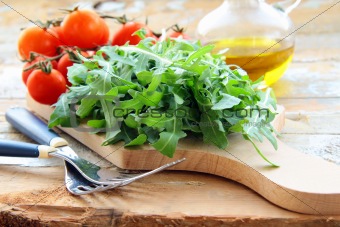 ingredients for the salad tomato and arugula on the kitchen board