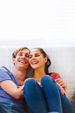 Young couple sitting at couch and laughing 
