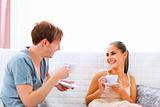 Young couple sitting at couch and drinking coffee
