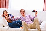 Young man taking joystick from his winning girlfriend while playing console
