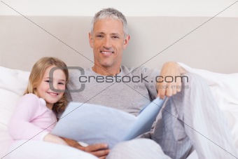 Smiling father reading a story to his daughter