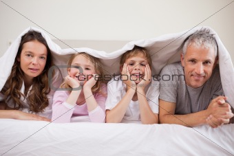 Family lying under a duvet