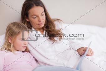 Little girl reading a book with her mother