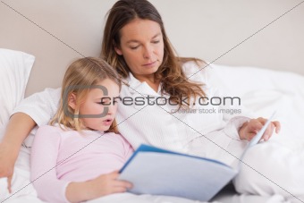 Cute girl reading a book with her mother