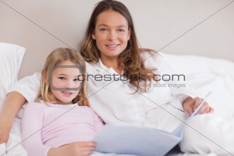 Smiling girl reading a book with her mother