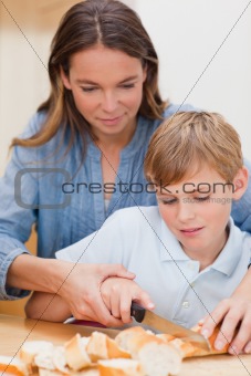 Portrait of a woman slicing bread with her son