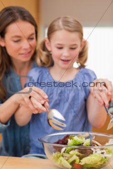 Portrait of a woman preparing a salad with her daughter