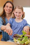 Portrait of a happy woman preparing a salad with her daughter