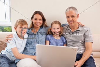 Smiling family sitting on a sofa using a notebook