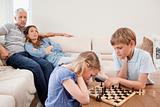 Children playing chess in front of their parents
