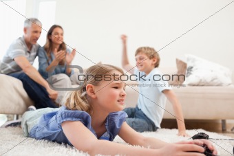 Cute children playing video games with their parents on the background