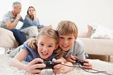 Cheerful children playing video games with their parents on the background
