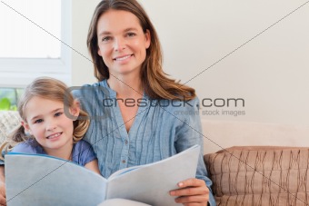Happy mother reading a book to her daughter