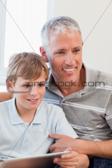 Portrait of a smiling father and his son using a tablet computer