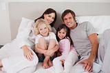 Smiling family posing on a bed