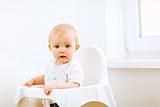 Lovely baby sitting in baby chair
