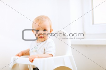 Lovely baby sitting in baby chair
