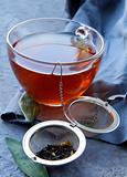 tea strainer with a fragrant black tea and cups in the background