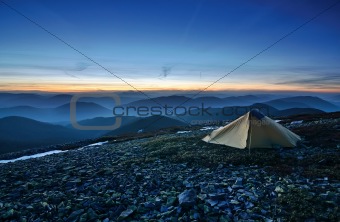 Tourist tent in the rocky mountains and first star