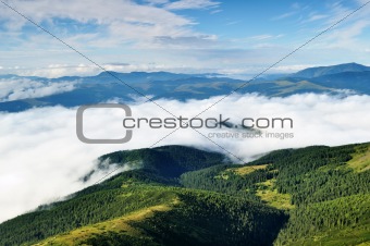 Landscape with mountains and forests under clouds 