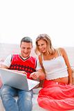 Happy young man showing his pregnant wife something in laptop

