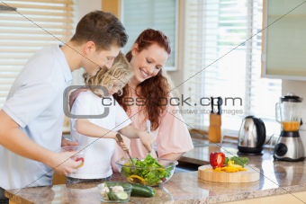 Couple letting their child stir the salad