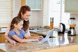 Mother and daughter with laptop in the kitchen