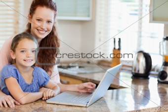 Mother and daughter surfing the internet in the kitchen