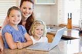 Mother with children on them laptop in the kitchen