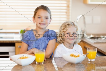 Siblings with breakfast behind the kitchen counter